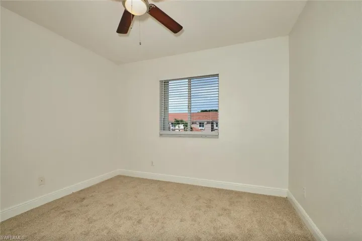 Carpeted empty room with baseboards and a ceiling fan