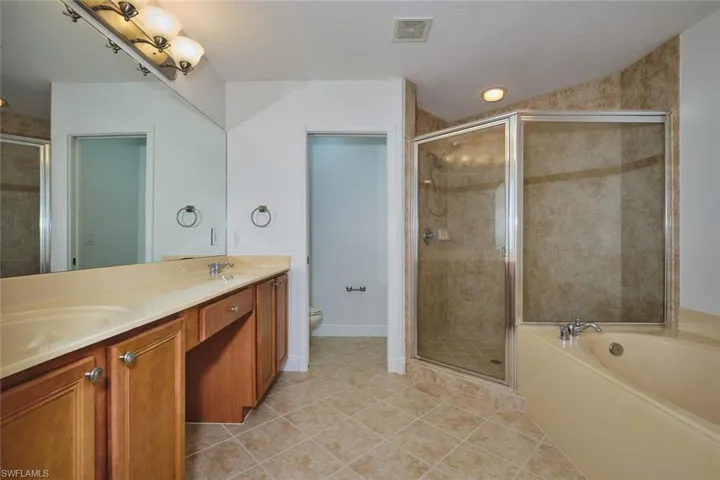 Bathroom with light tile patterned floors, a shower stall, and a garden tub