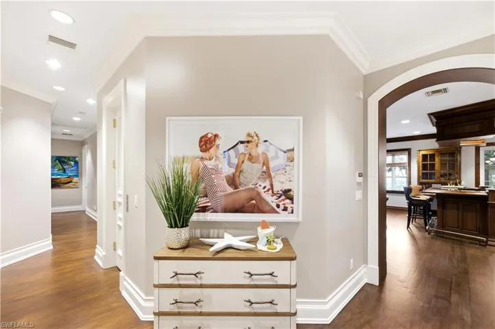 Hardwood flooring, recessed lighting, crown molding, arched entryway, and baseboard trim