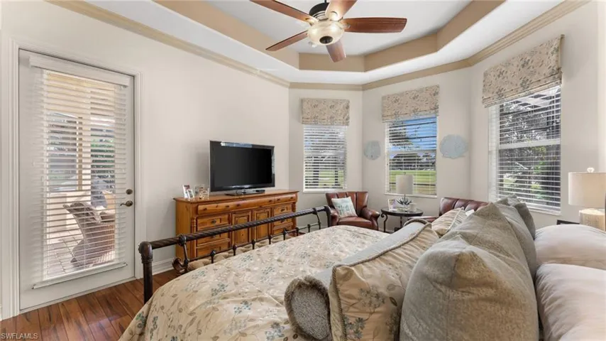 Master Bedroom with hardwood / wood-style floors, ceiling fan, a raised ceiling, and access to exterior lanai & pool.