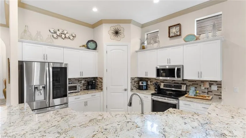 Kitchen with white cabinets, stainless steel appliances, and tasteful backsplash