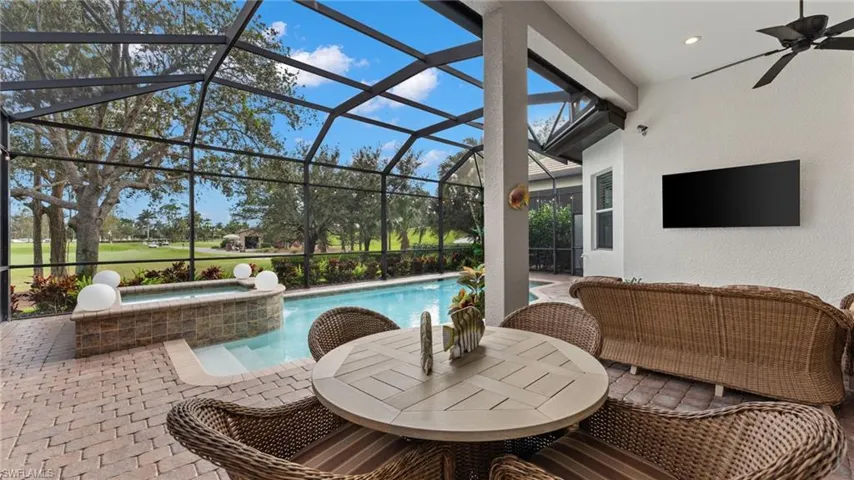 View of pool featuring glass enclosure, an in ground hot tub, ceiling fan, and a patio