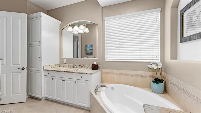 Master Bathroom featuring tiled bath, tile patterned flooring, and vanity