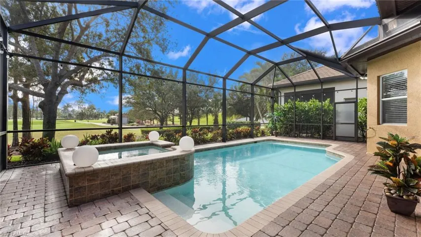 View of pool featuring an in ground hot tub, a patio, and glass enclosure