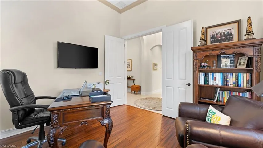 Office space with crown molding, wood-type flooring, and a high ceiling