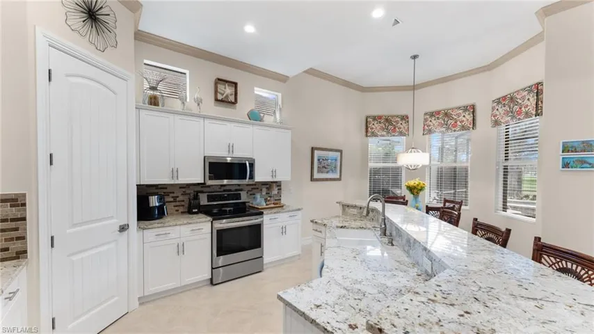 Kitchen with pendant lighting, white cabinetry, sink, and appliances with stainless steel finishes