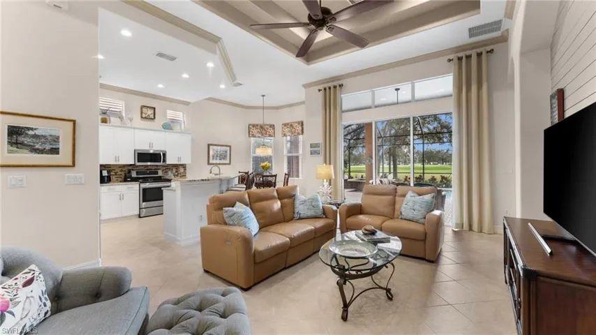 Living room with ceiling fan, light tile patterned flooring, and crown molding