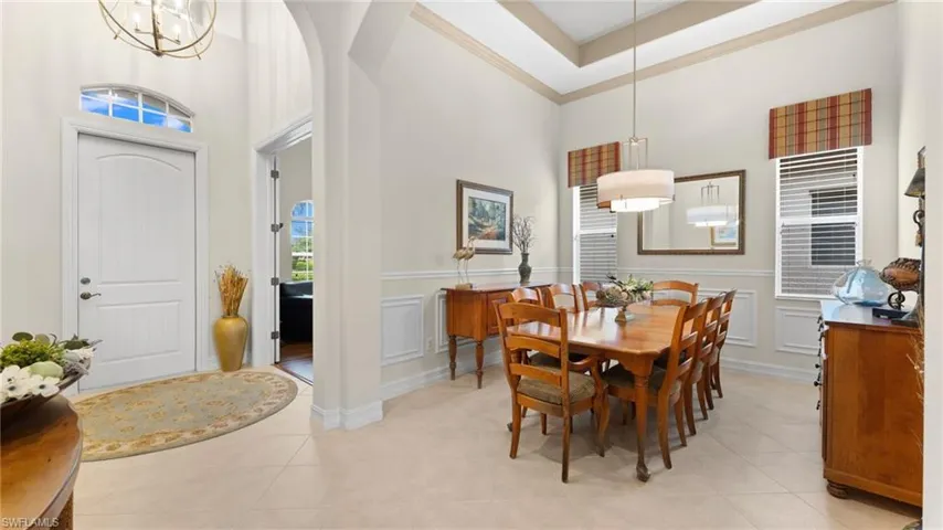 Tiled dining space with a chandelier, a towering ceiling, and crown molding