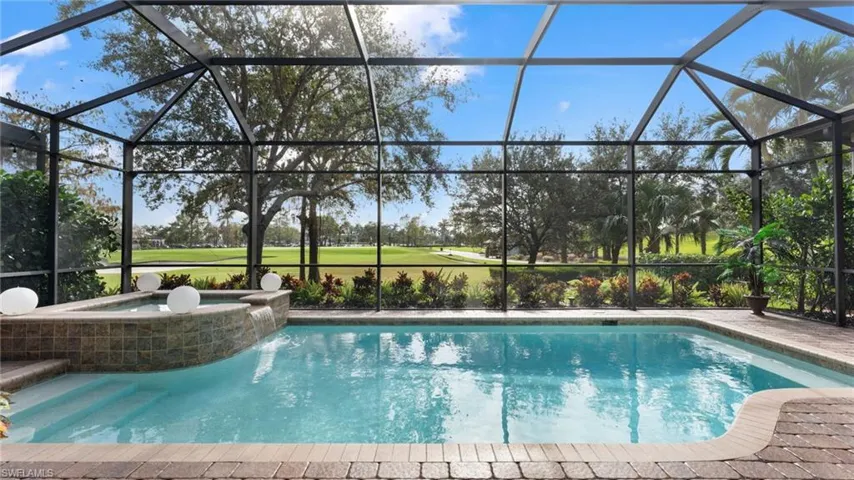 View of pool featuring glass enclosure and an in ground hot tub