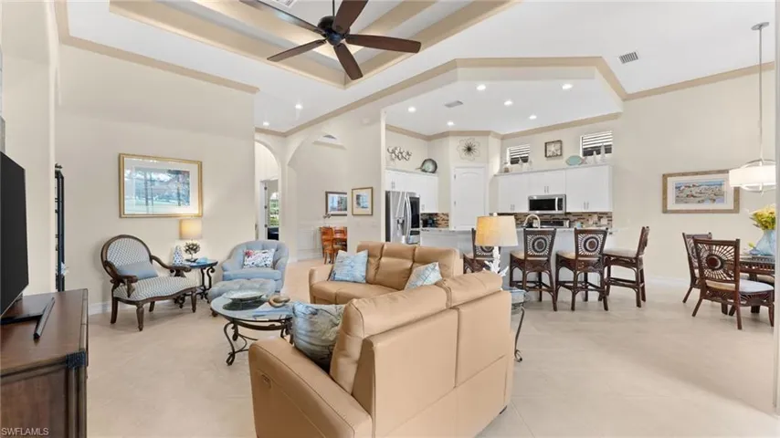Tiled living room with ceiling fan, a high ceiling, and ornamental molding