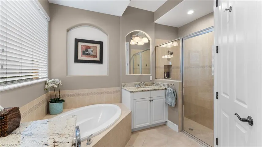 Master Bathroom with tile patterned floors, vanity, and plus walk in shower