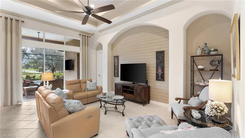Living room featuring ceiling fan, a raised ceiling, and light tile patterned floors
