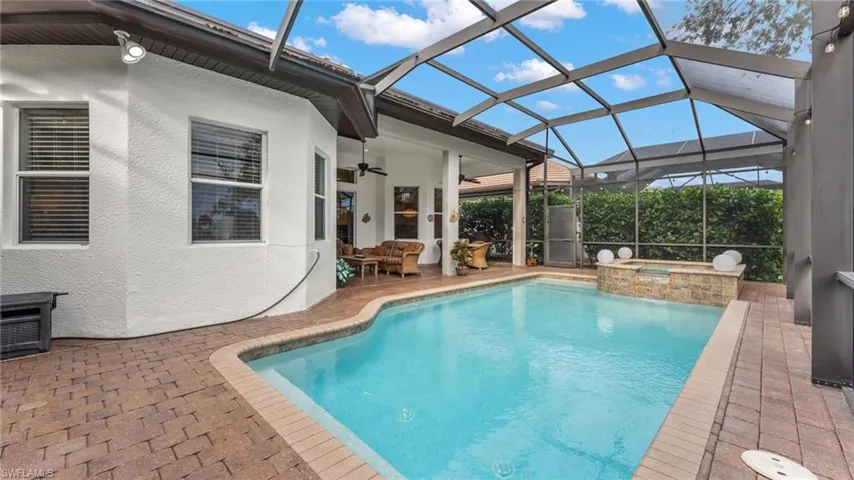 View of pool with glass enclosure, ceiling fan, a patio, and an in ground hot tub