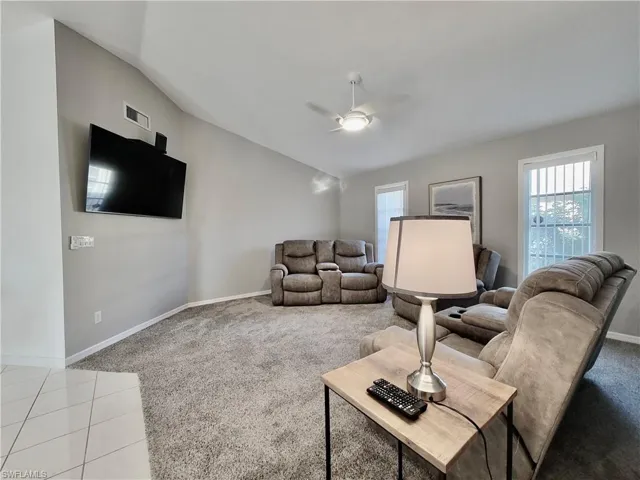 Carpeted living room featuring vaulted ceiling and ceiling fan