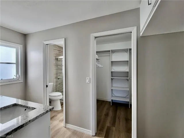 Bathroom in primary suite, featuring vanity. with dual sinks, a tile shower, hardwood / wood-style floors