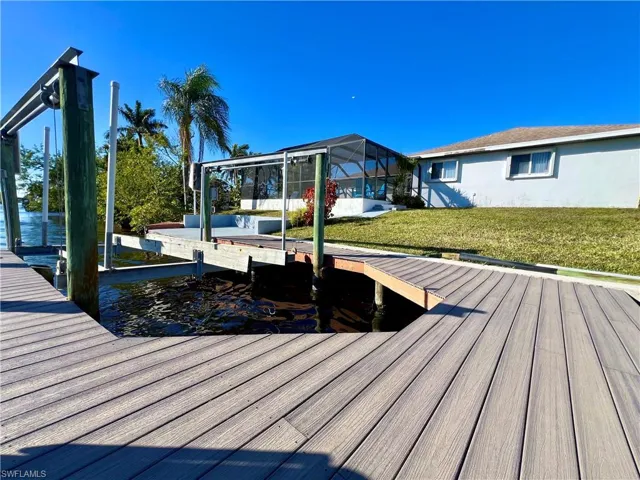 Composite dock area with electric boat lift featuring the back yard and view of lanai