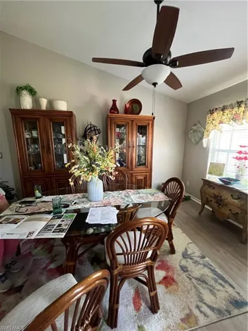 Vaulted ceiling with a ceiling fan, light-toned walls, and wood-finish flooring