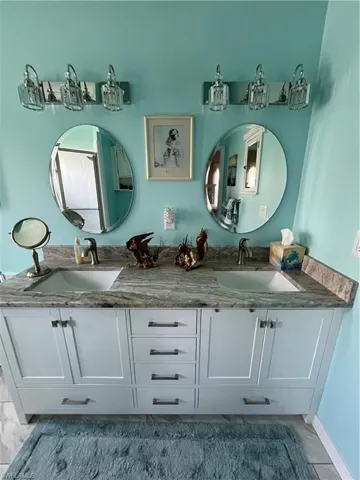 Double vanity with a granite countertop, dual undermount sinks, and white shaker-style cabinetry