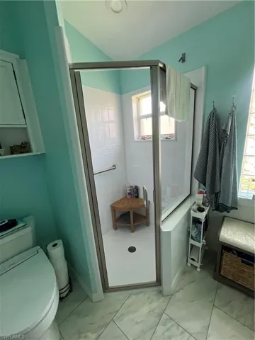 Glass-enclosed shower with a built-in grab bar and corner window