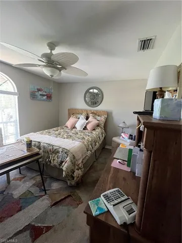 Bedroom featuring a ceiling fan with integrated lighting, an arched window, textured wall-to-wall carpeting, and neutral wall tones