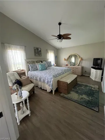 Spacious room featuring vaulted ceilings, wood-finish flooring, and a ceiling fan with light fixture
