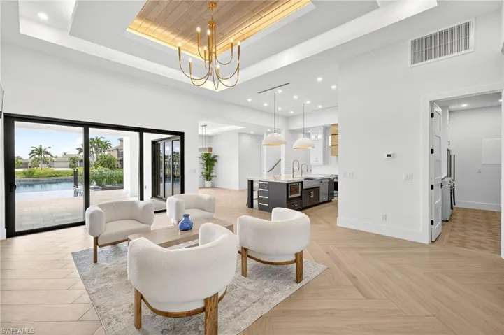 Living room featuring a tray ceiling, recessed lighting, a high ceiling, and a chandelier