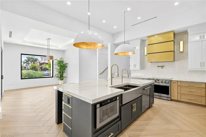 Kitchen with tasteful backsplash, light stone countertops, hanging light fixtures, white cabinetry, and appliances with stainless steel finishes