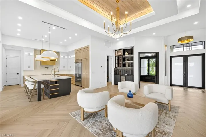 Living area featuring a tray ceiling, recessed lighting, french doors, a towering ceiling, and a chandelier