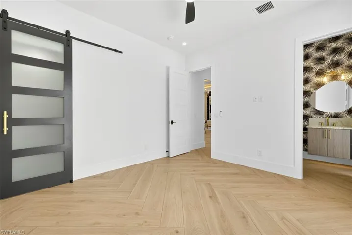 Unfurnished bedroom featuring a barn door, a walk in closet, ceiling fan, and recessed lighting