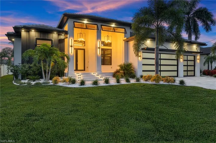 Contemporary house featuring an attached garage, a yard, driveway, stucco siding, and entry steps