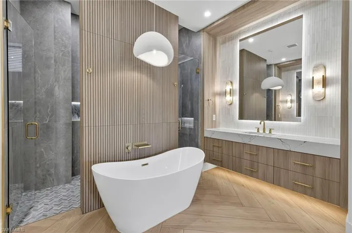 Full bath featuring tile walls, a freestanding bath, a stall shower, and vanity
