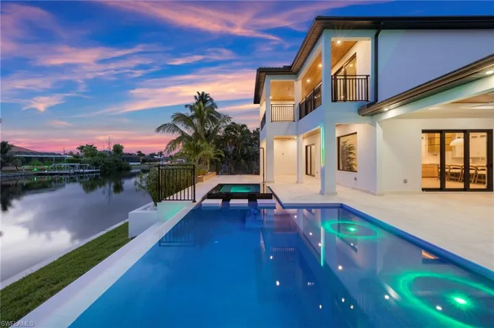 View of swimming pool with a balcony, a patio area, a pool with connected hot tub, and a water view