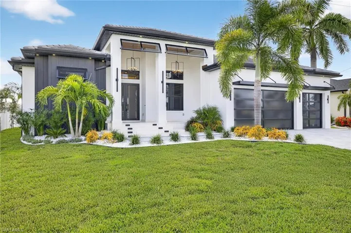 View of front of home featuring an attached garage, a front lawn, concrete driveway, and stucco siding