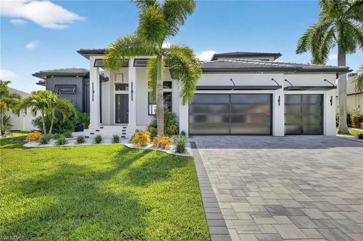 View of front of house featuring decorative driveway, a garage, a front lawn, stucco siding, and a tiled roof