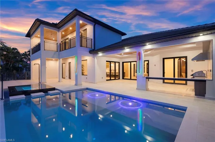 Rear view of house with a patio, a balcony, a pool with connected hot tub, and stucco siding