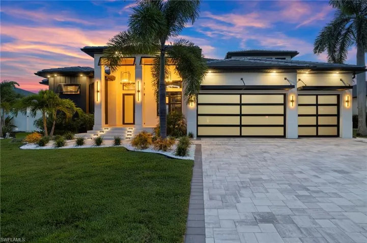 View of front facade with a garage, decorative driveway, a tile roof, a front lawn, and stucco siding