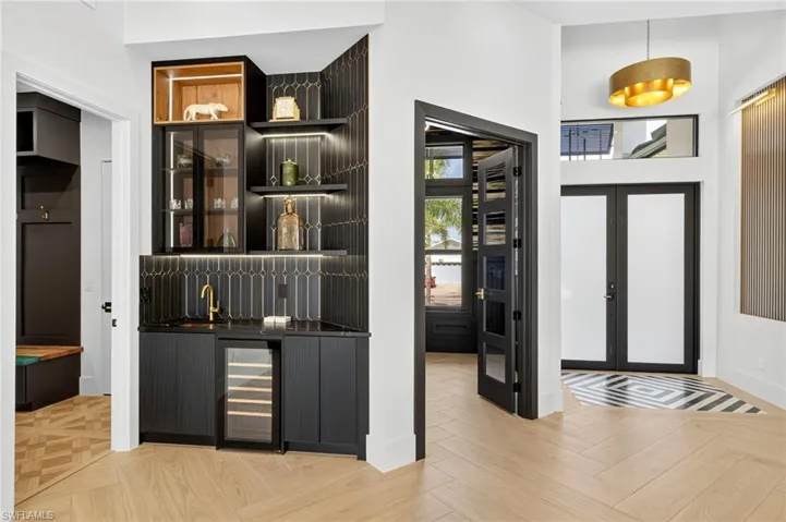 Indoor wet bar featuring open shelves, dark cabinetry, french doors, and wine cooler