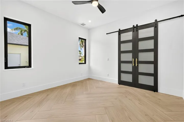 Unfurnished room featuring a barn door, ceiling fan, and recessed lighting