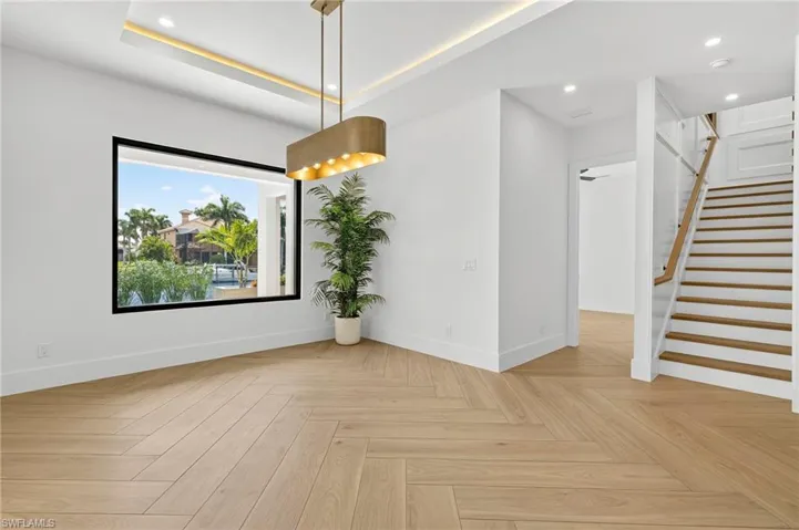 Unfurnished dining area featuring stairway, recessed lighting, and a tray ceiling
