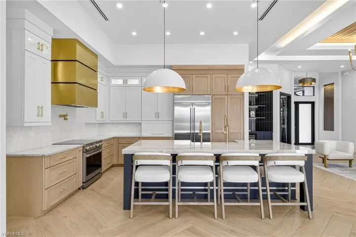 Kitchen featuring glass insert cabinets, light stone counters, decorative light fixtures, and recessed lighting