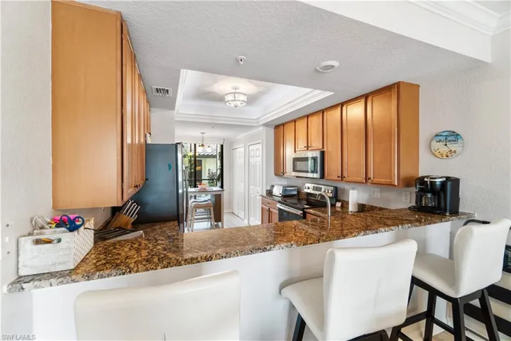 Kitchen with stainless steel appliances, a tray ceiling, a breakfast bar, and kitchen peninsula
