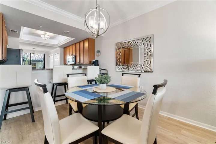 Dining room with a chandelier, a tray ceiling, light wood-type flooring, and ornamental molding