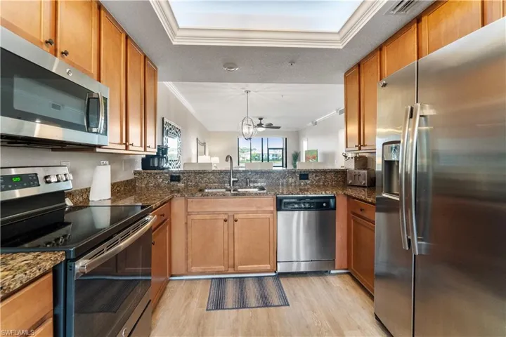 Kitchen with light hardwood / wood-style floors, kitchen peninsula, ceiling fan, appliances with stainless steel finishes, and sink