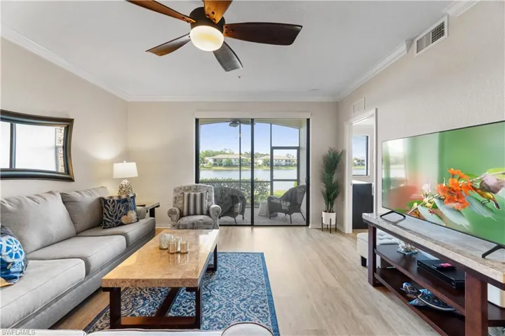 Living room with crown molding, ceiling fan, a water view, and light hardwood / wood-style flooring