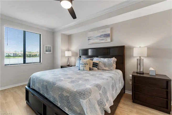 Bedroom with ceiling fan, light wood-type flooring, and ornamental molding