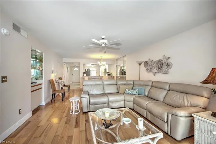 Living room featuring ceiling fan with notable chandelier and light wood-type flooring