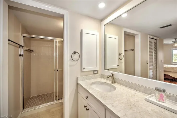 Bathroom featuring an enclosed shower, vanity, ceiling fan, and tile patterned flooring