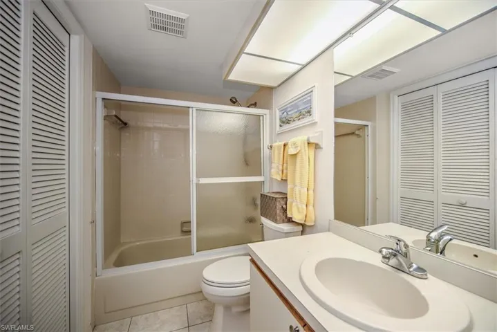 Full bathroom with tile patterned floors, vanity, toilet, and bath / shower combo with glass door