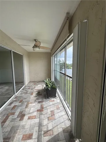 Lanai featuring a textured wall, a water view, and brick flooring