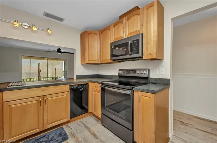 Eat in Kitchen featuring stainless steel appliances, a wainscoted wall, dark countertops, light wood finished floors, under counter water filtration and Bosch dishwasher